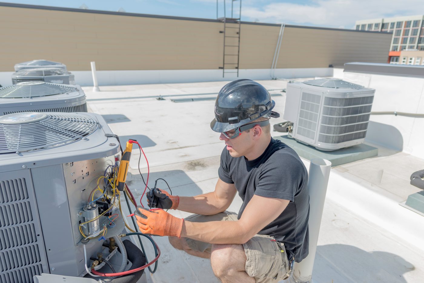 Technician servicing rooftop commercial HVAC equipment, representative of NCIS commercial services.