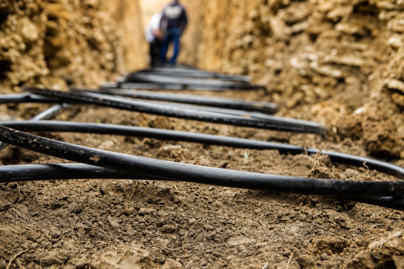 Geothermal ground-loop piping coiled along the floor of an open trench during a North Central Iowa installation, with the crew working at the far end.