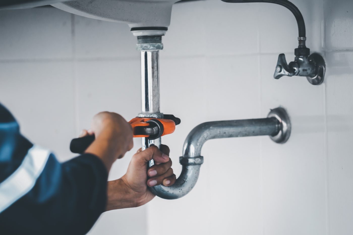 Plumber replacing a sink P-trap during a residential repair, representative of NCIS plumbing services.